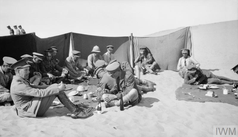 © IWM (Q 57819) men sheltering from sand and having lunch